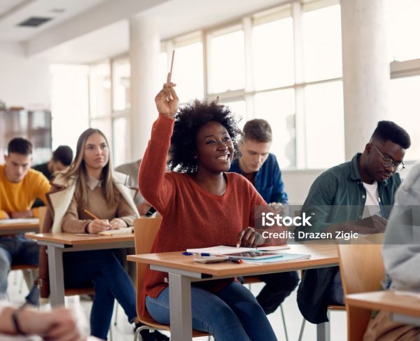 Happy African American student raising her hand to ask a question during lecture in the classroom.