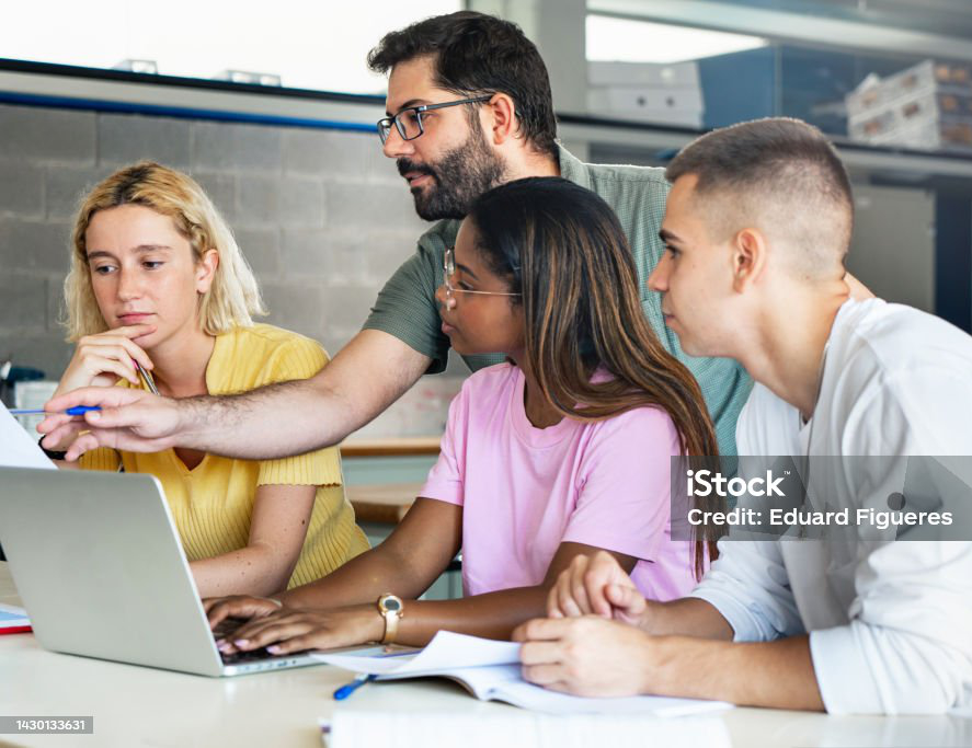 Young teacher helping teenager students at College, learning technology and science in preparatory course for university