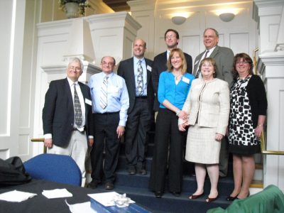 group of professionals on a staircase showing off their award plaques
