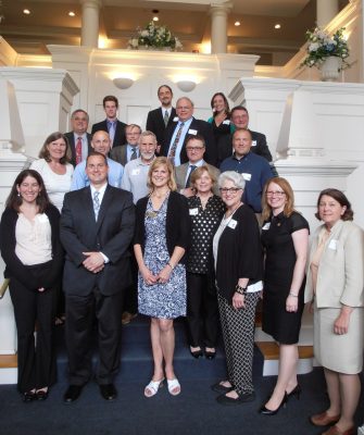 group of professionals on a staircase showing off their award plaques