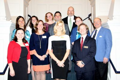 group of professionals on a staircase showing off their award plaques