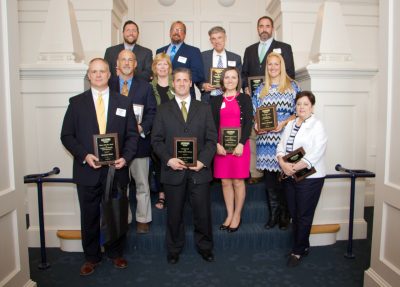 group of professionals on a staircase showing off their award plaques