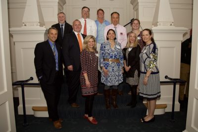 group of professionals on a staircase showing off their award plaques