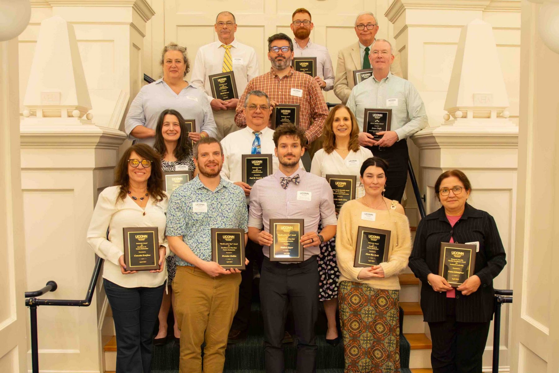 group of professionals on a staircase showing off their award plaques