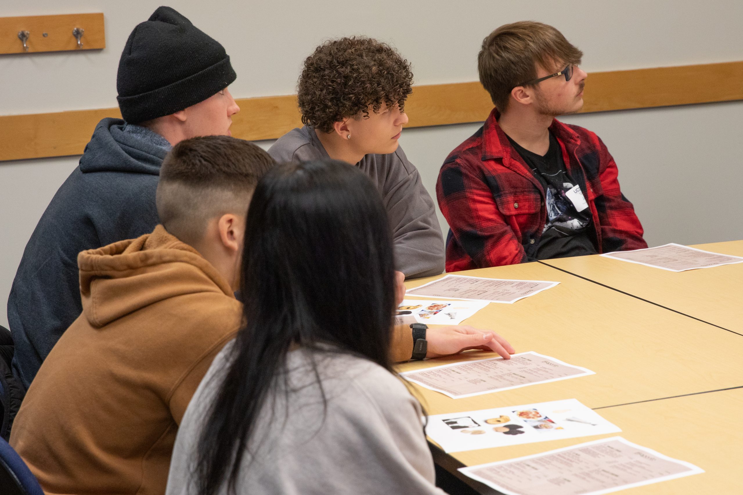 5 students gathered around the corner of a table