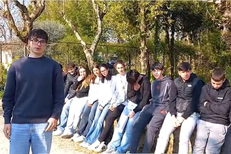 Group of students sitting along a stone wall with one student speaking in the foreground